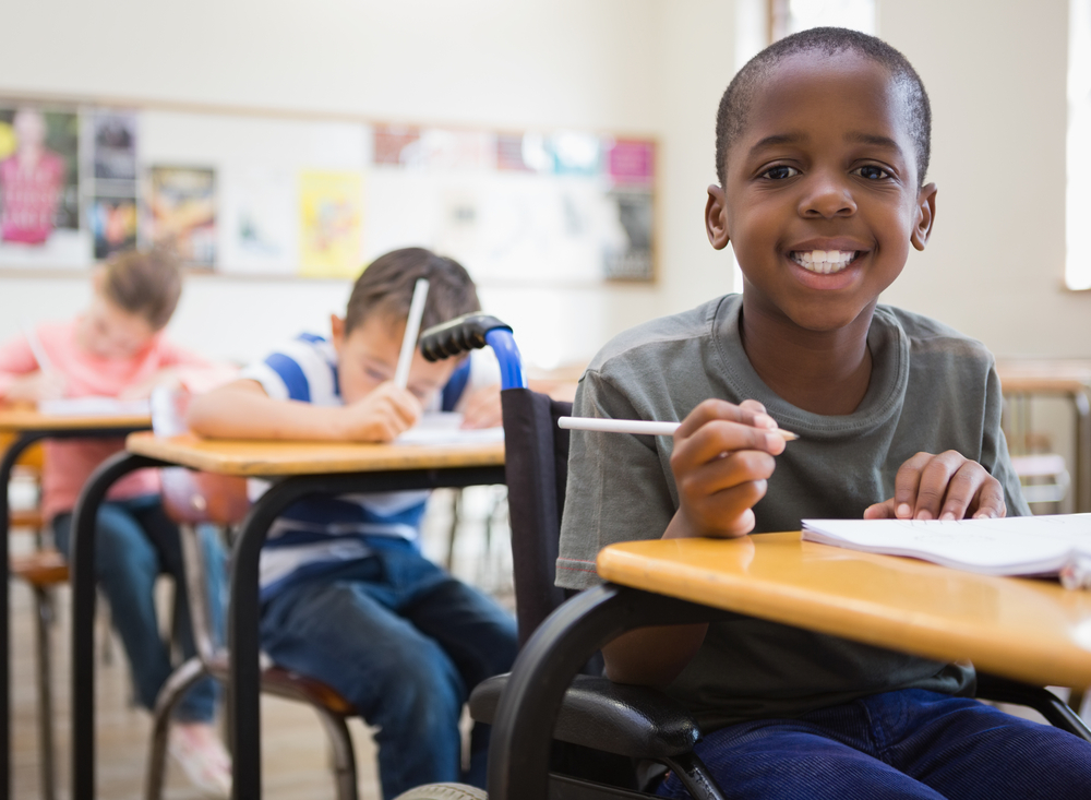 Disabled pupil smiling at camera in classroom at the elementary school